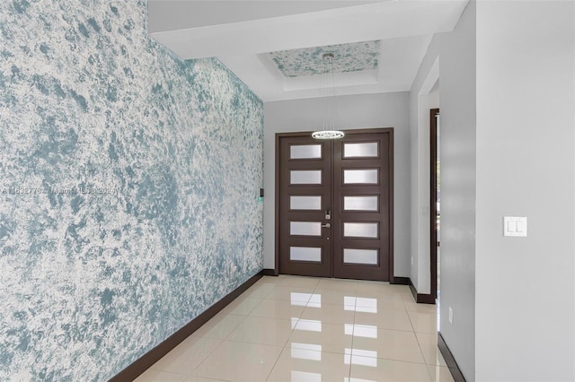 tiled foyer entrance with french doors and a tray ceiling