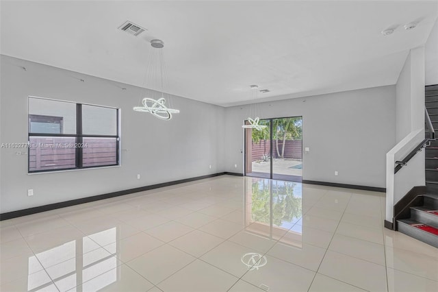 tiled empty room with an inviting chandelier