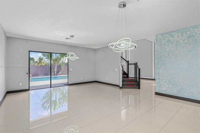 tiled spare room with a chandelier