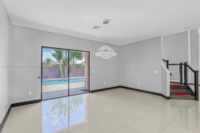 tiled empty room with a chandelier