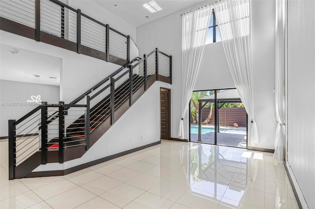 stairway featuring a towering ceiling and light tile patterned floors