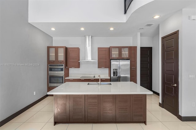 kitchen featuring light tile patterned flooring, a center island with sink, wall chimney exhaust hood, appliances with stainless steel finishes, and sink