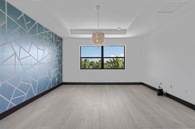 spare room featuring a chandelier, hardwood / wood-style floors, and a tray ceiling