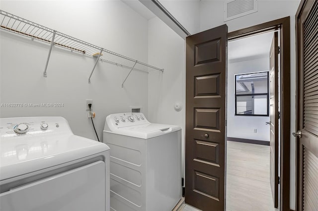 washroom with independent washer and dryer and light hardwood / wood-style flooring