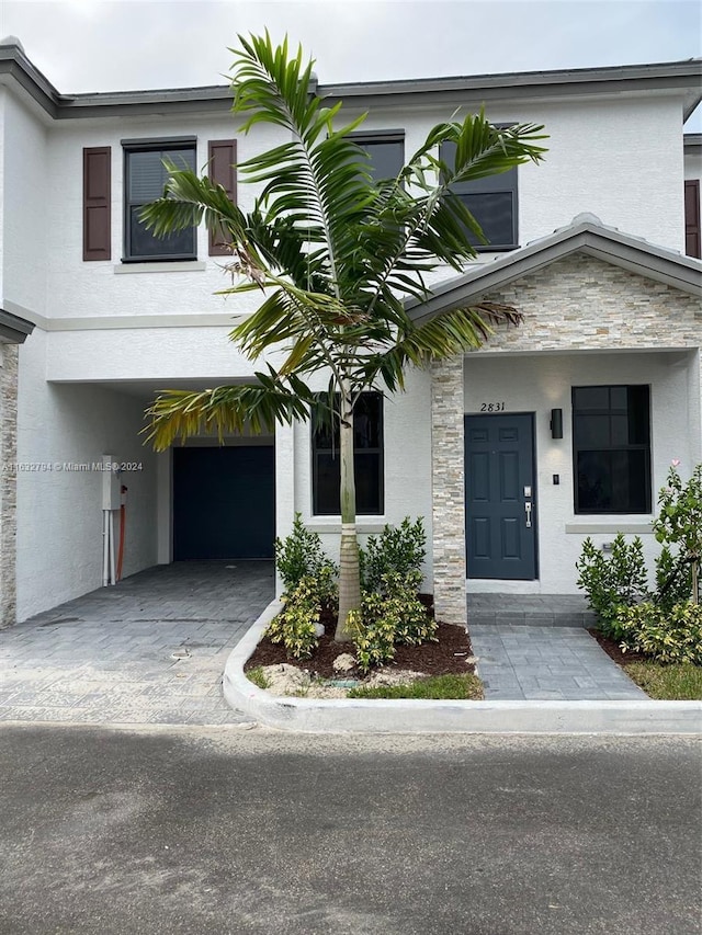 view of front of home with driveway, stone siding, and stucco siding