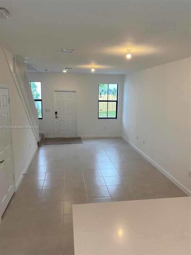 interior space featuring stairs, visible vents, plenty of natural light, and light tile patterned floors