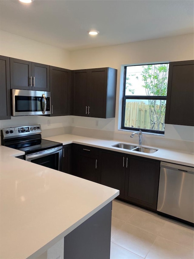 kitchen with light tile patterned floors, recessed lighting, a sink, light countertops, and appliances with stainless steel finishes