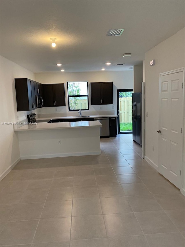 kitchen featuring appliances with stainless steel finishes, light countertops, a sink, and light tile patterned flooring