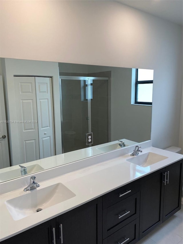 bathroom with tile patterned flooring, a shower with door, vanity, and toilet