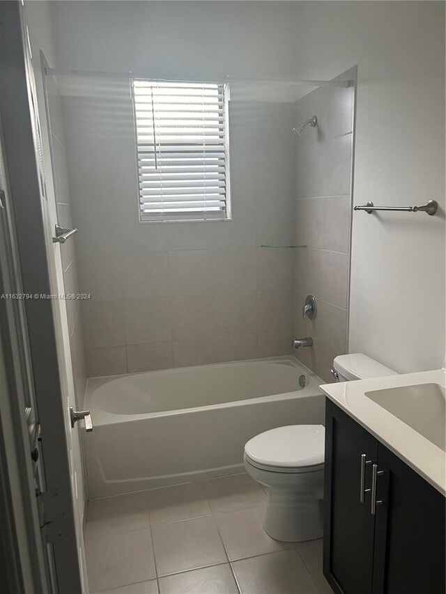 full bathroom with tiled shower / bath combo, toilet, tile patterned floors, and vanity