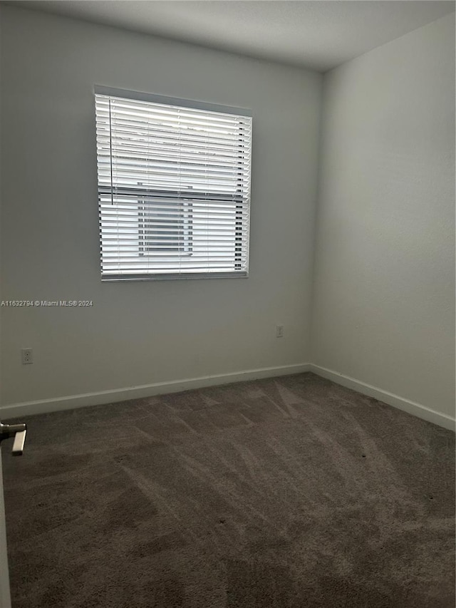 carpeted spare room featuring baseboards