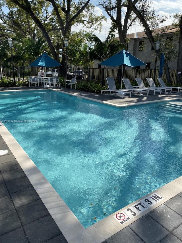 community pool with fence and a patio