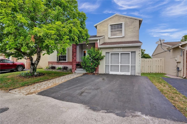 view of front of home featuring a garage, driveway, fence, and stucco siding