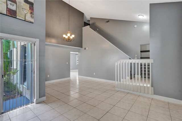 empty room featuring a chandelier, high vaulted ceiling, and light tile patterned floors