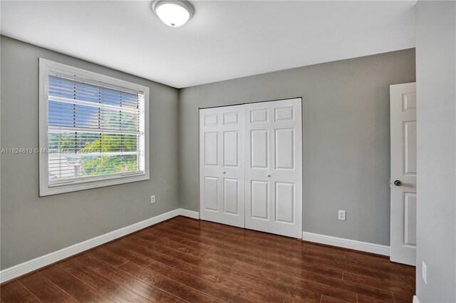 unfurnished bedroom with dark hardwood / wood-style floors and a closet