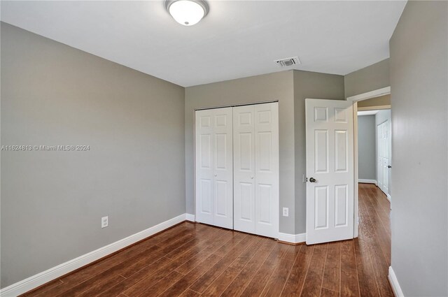 unfurnished bedroom featuring dark hardwood / wood-style floors and a closet