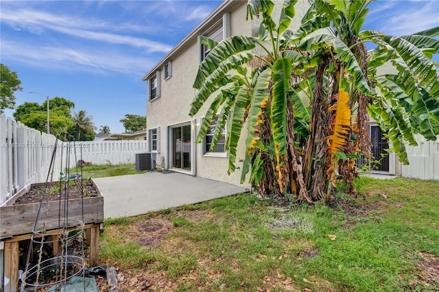 rear view of house with a vegetable garden, a patio, stucco siding, cooling unit, and a fenced backyard