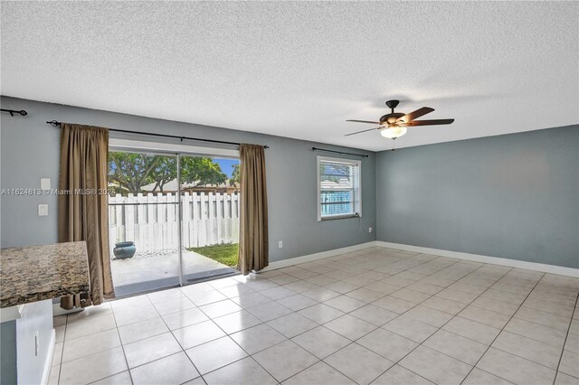 empty room with light tile patterned flooring, a textured ceiling, and ceiling fan