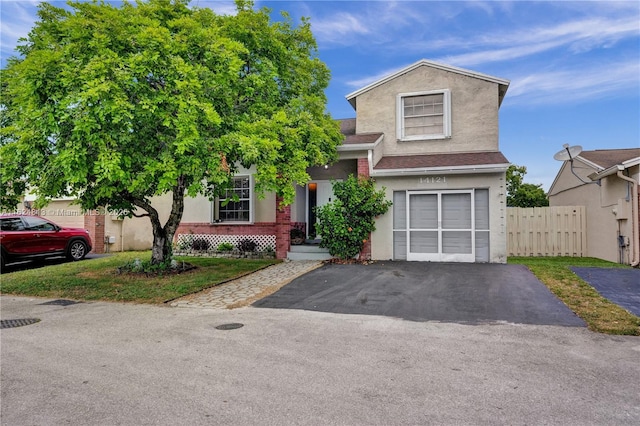 view of front facade with aphalt driveway, fence, an attached garage, and stucco siding