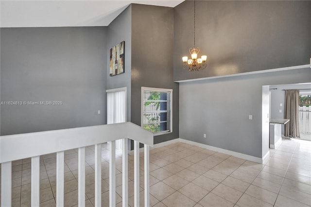 interior space with a high ceiling, a notable chandelier, baseboards, and light tile patterned floors