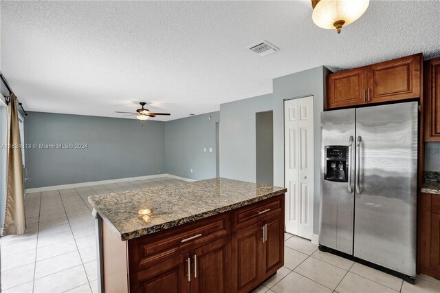 kitchen with ceiling fan, stainless steel fridge with ice dispenser, stone countertops, a textured ceiling, and light tile patterned floors