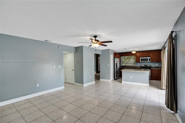 kitchen featuring light tile patterned flooring, stainless steel appliances, a center island, and ceiling fan