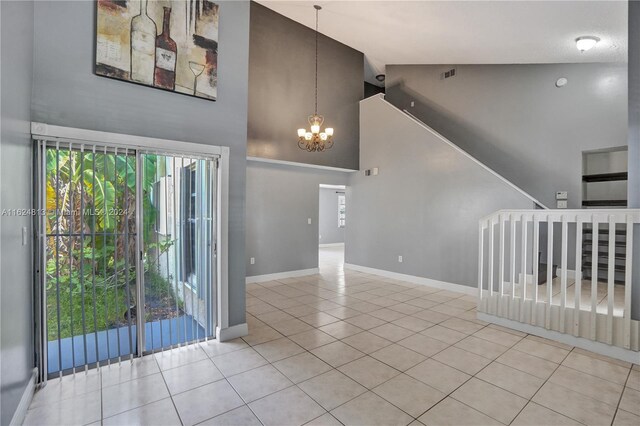 empty room featuring a notable chandelier, light tile patterned floors, and high vaulted ceiling