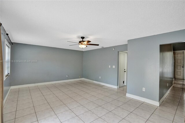 tiled spare room with a textured ceiling and ceiling fan