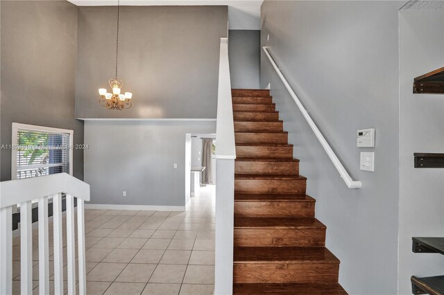 stairs featuring tile patterned flooring, a towering ceiling, and a chandelier