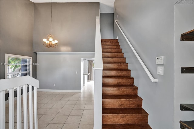 staircase with tile patterned flooring, a high ceiling, a notable chandelier, and baseboards