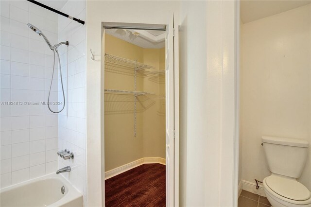 bathroom with toilet, tiled shower / bath, and hardwood / wood-style floors