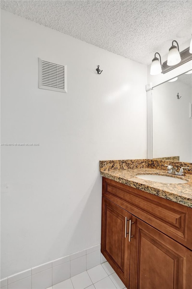 bathroom with baseboards, visible vents, tile patterned flooring, a textured ceiling, and vanity