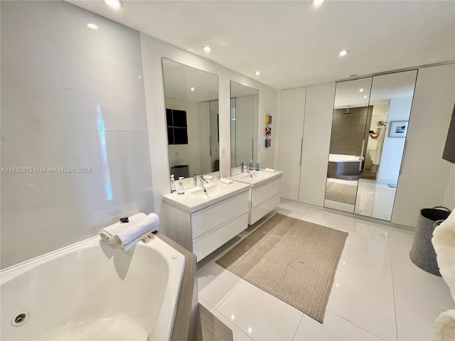 bathroom with tile patterned floors, a bathing tub, and vanity