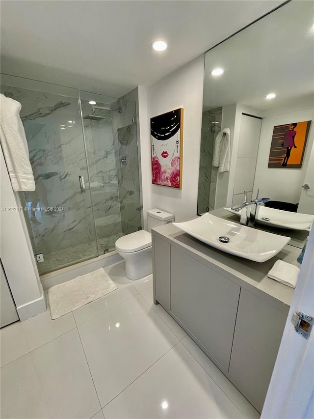 bathroom with vanity, a shower with door, toilet, and tile patterned flooring