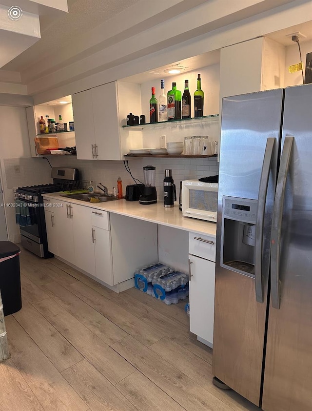 kitchen with light wood-type flooring, white cabinetry, and stainless steel appliances