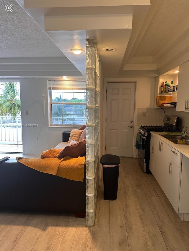 bedroom with a textured ceiling, sink, access to outside, and light hardwood / wood-style floors