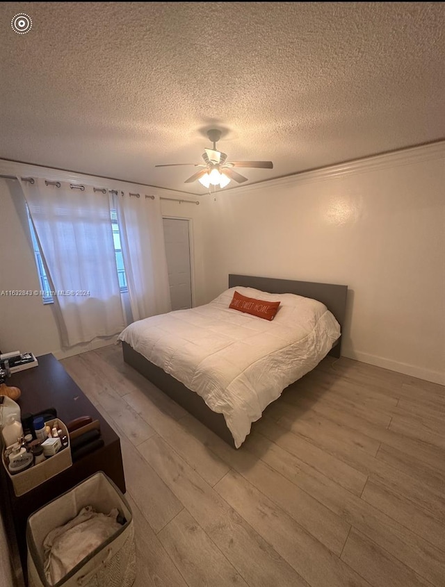 bedroom with a textured ceiling, ceiling fan, and wood-type flooring