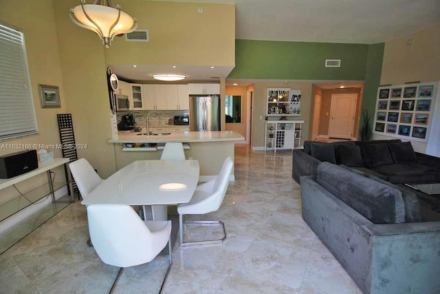 dining area with a towering ceiling, sink, and light tile patterned floors