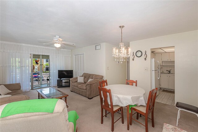 dining space with ceiling fan with notable chandelier, light carpet, and sink