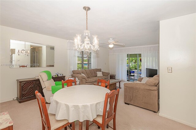 carpeted dining room with a wealth of natural light and ceiling fan with notable chandelier