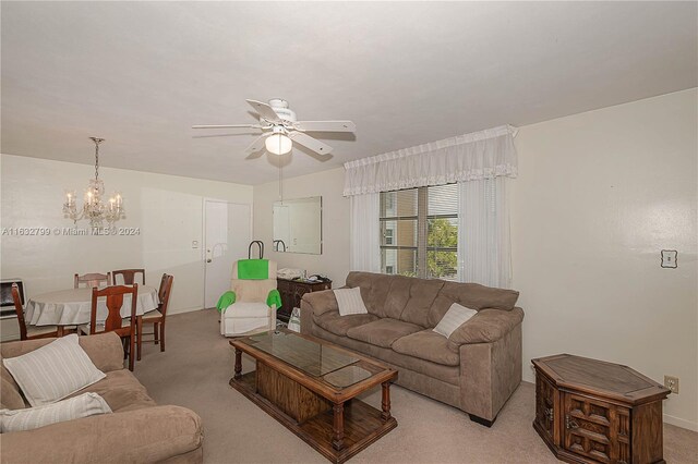 living room featuring ceiling fan with notable chandelier and light colored carpet