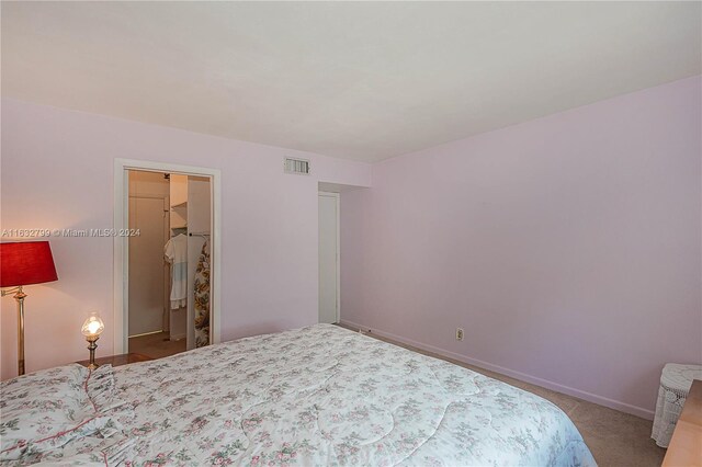 carpeted bedroom featuring a spacious closet and a closet