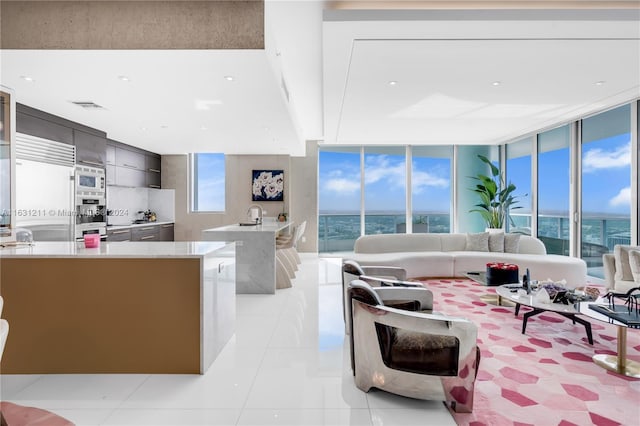 interior space featuring sink, light tile patterned floors, a center island with sink, floor to ceiling windows, and high end refrigerator