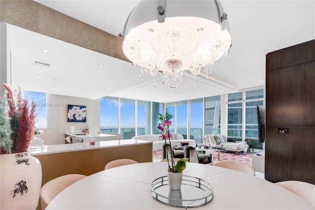 dining space featuring a wall of windows, a water view, and a chandelier