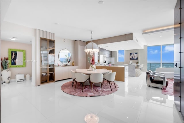 tiled dining space featuring a notable chandelier and a water view