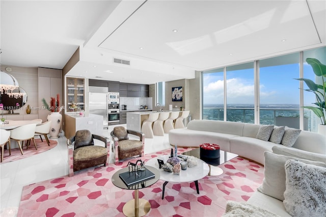 living room featuring floor to ceiling windows, a water view, and sink