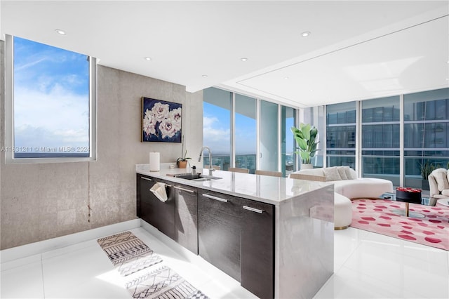 kitchen with light tile patterned floors, a wall of windows, sink, and light stone countertops