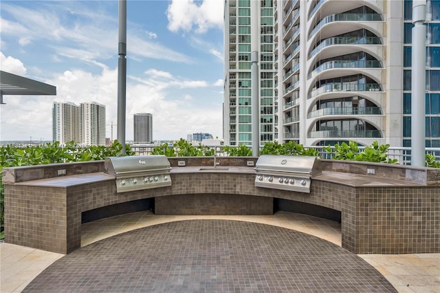 view of patio with a balcony, sink, a grill, and exterior kitchen