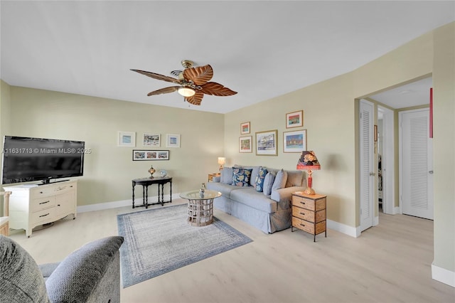 living area featuring light wood-style flooring, baseboards, and ceiling fan