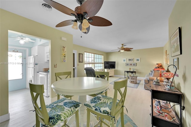 dining space featuring a ceiling fan, light wood-style floors, and baseboards